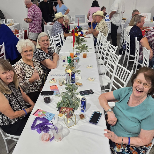 Guests laughing and smiling at a table during Taste of Milam, a CASA of Milam County fundraising event.