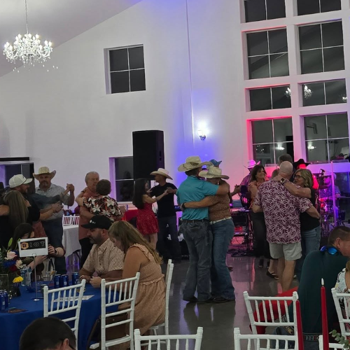 Guests dancing during Taste of Milam with live music and event seating in the background.
